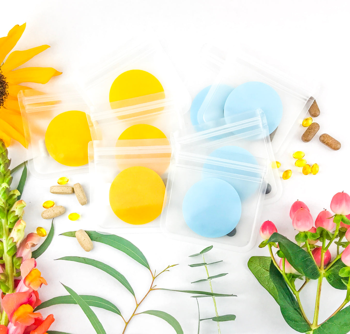 8 Vitamin & Supplement pill organizer pouches/bags surrounded by flowers. 4 pouches for morning and 4 pouches for evening supplements. Each bag is 3.25x3.25 inches.